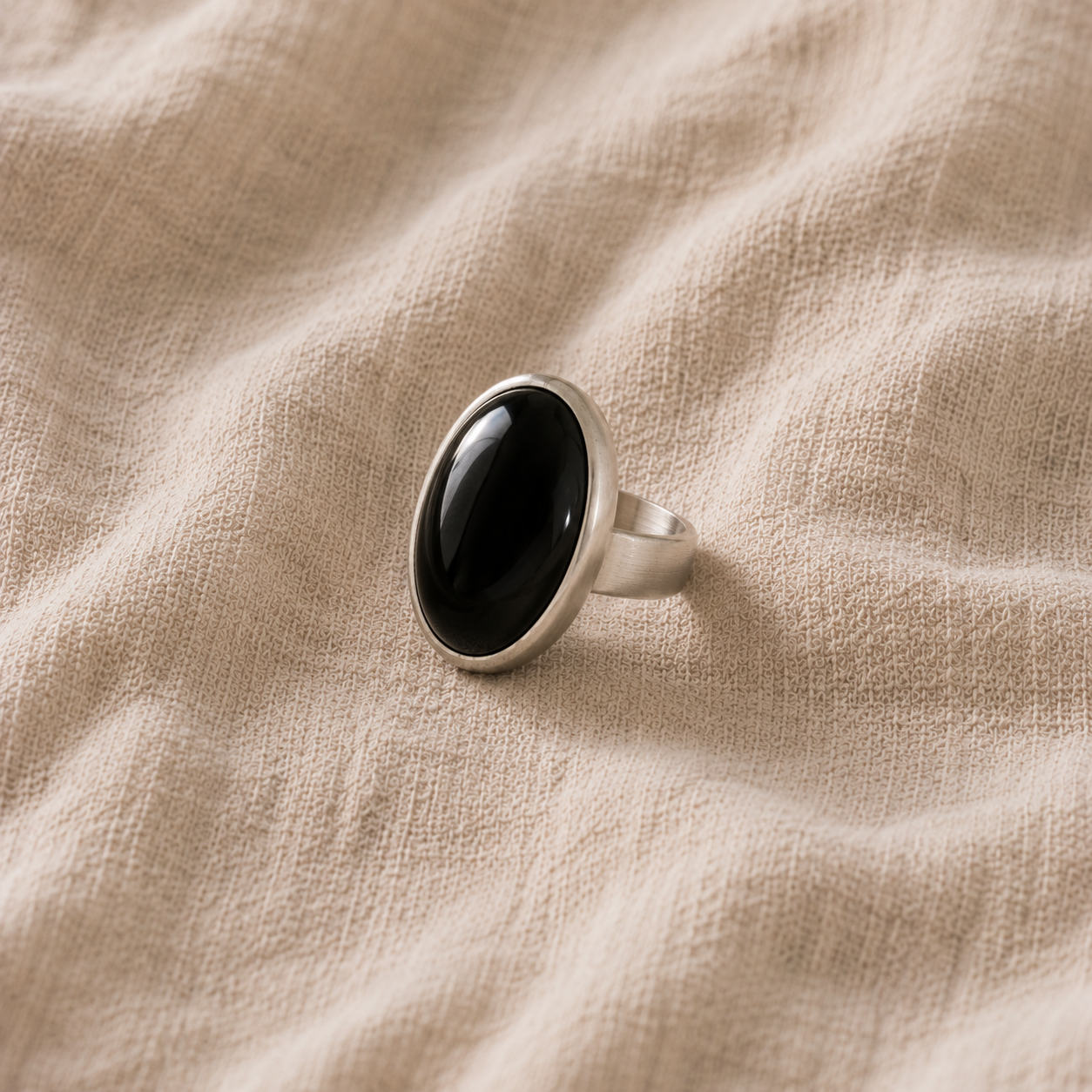 Un bijou en obsidienne est il fragile ? La réponse d'une créatrice Bague en argent sertie d une obsidienne noire posee sur du lin