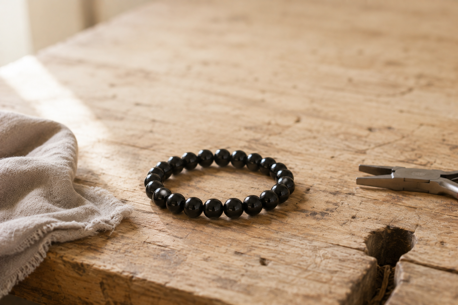 Un bijou en obsidienne est il fragile ? La réponse d'une créatrice Bracelet en perles d obsidienne noire pose sur un etabli de bijoutier