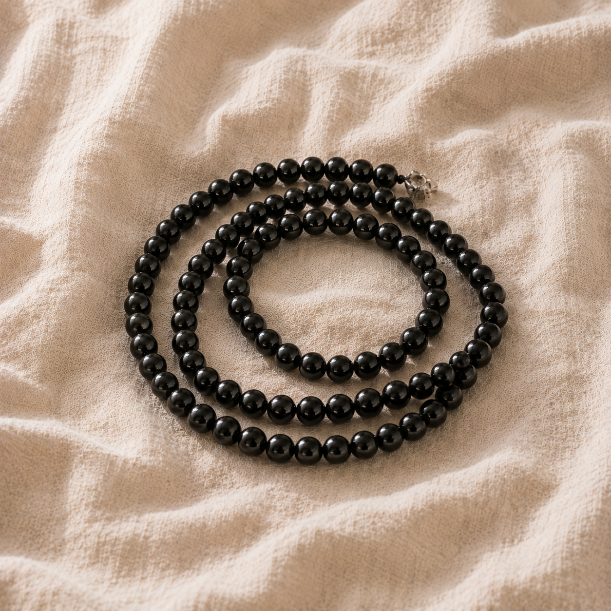 Un bijou en obsidienne est il fragile ? La réponse d'une créatrice Collier de perles d obsidienne noire enroule sur du bois clair