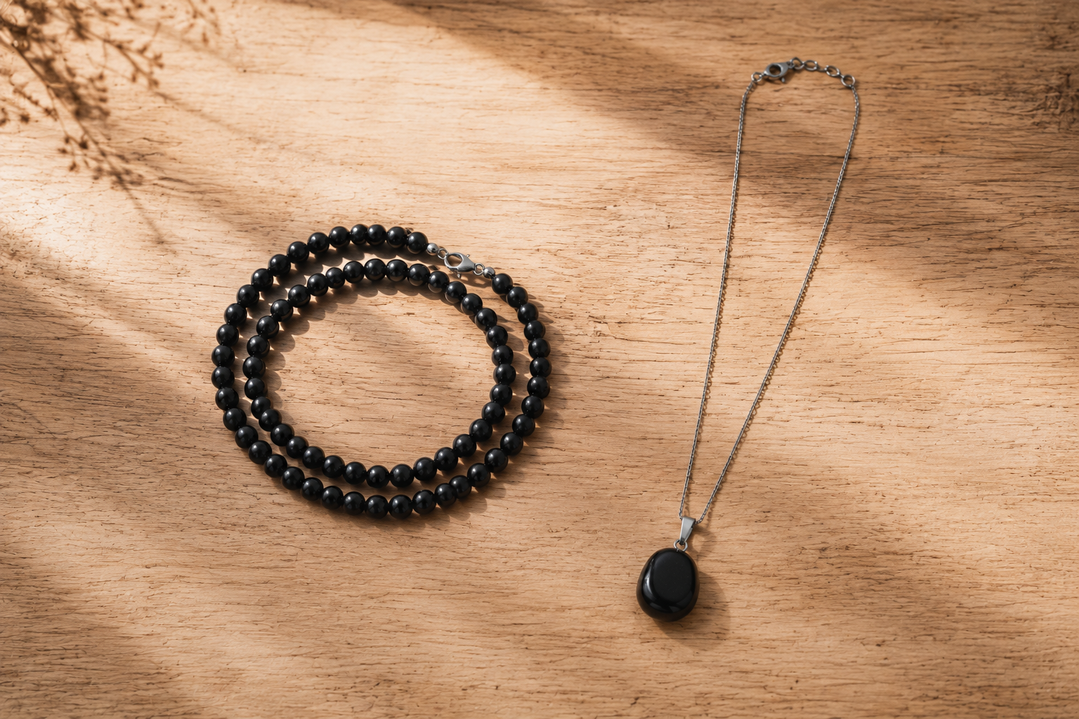 Rang de perles d'obsidienne et pierre unique sur chaîne posés côte à côte