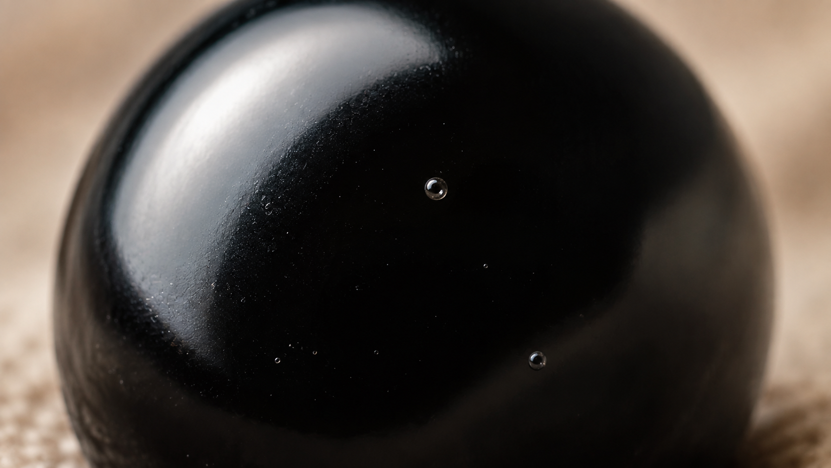 Macro de la surface vitreuse d'une perle d'obsidienne noire