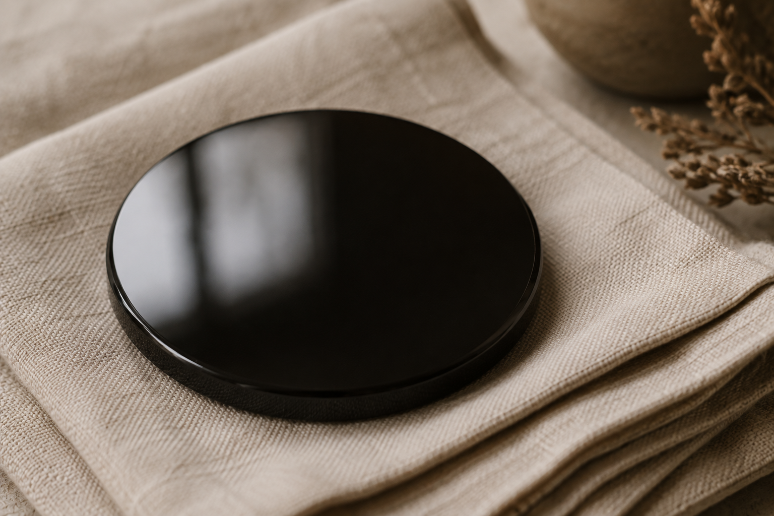 Polished black obsidian faintly reflecting light on linen