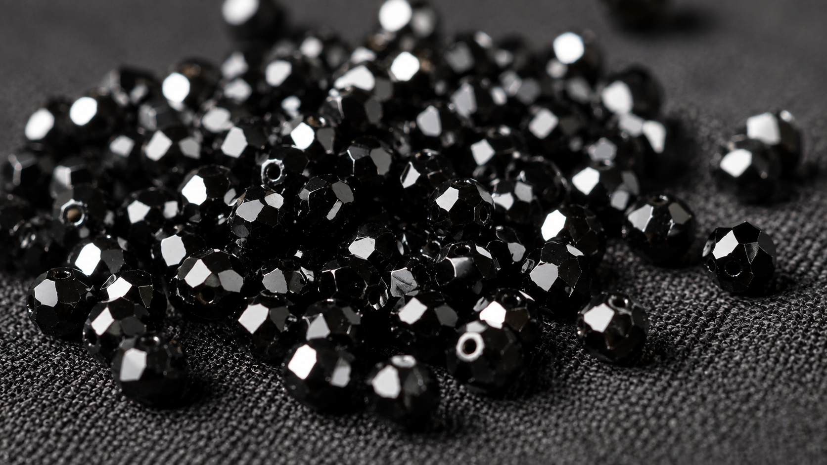Perles de spinelle noir à facettes vives sur fond de lin sombre