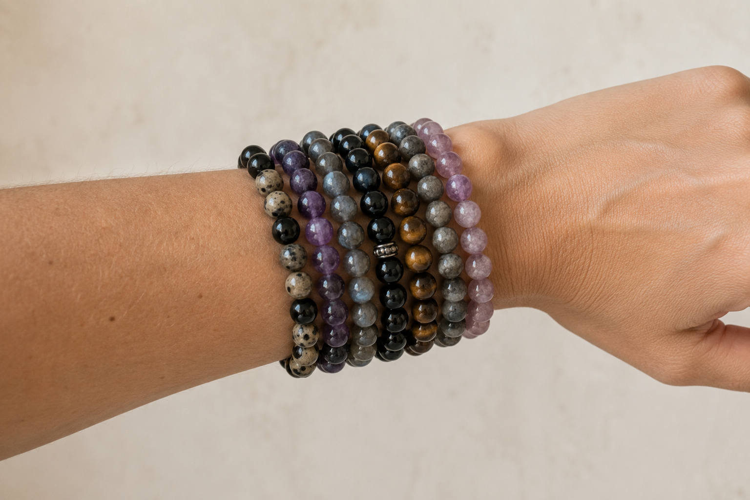 Poignet portant une pile de bracelets de pierres naturelles différentes