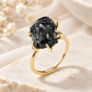 Bague dorée ajustable, bloc d'obsidienne brute tenu par quatre griffes en volute