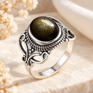 Bague en argent à arabesques ajourées et grènetis, cabochon ovale d'obsidienne dorée