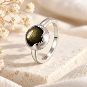 Bague en argent où un croissant poli recouvre en partie un petit cabochon d'obsidienne dorée