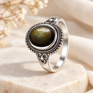 Bague en argent à épaules fleuries et grènetis, cabochon ovale d'obsidienne dorée