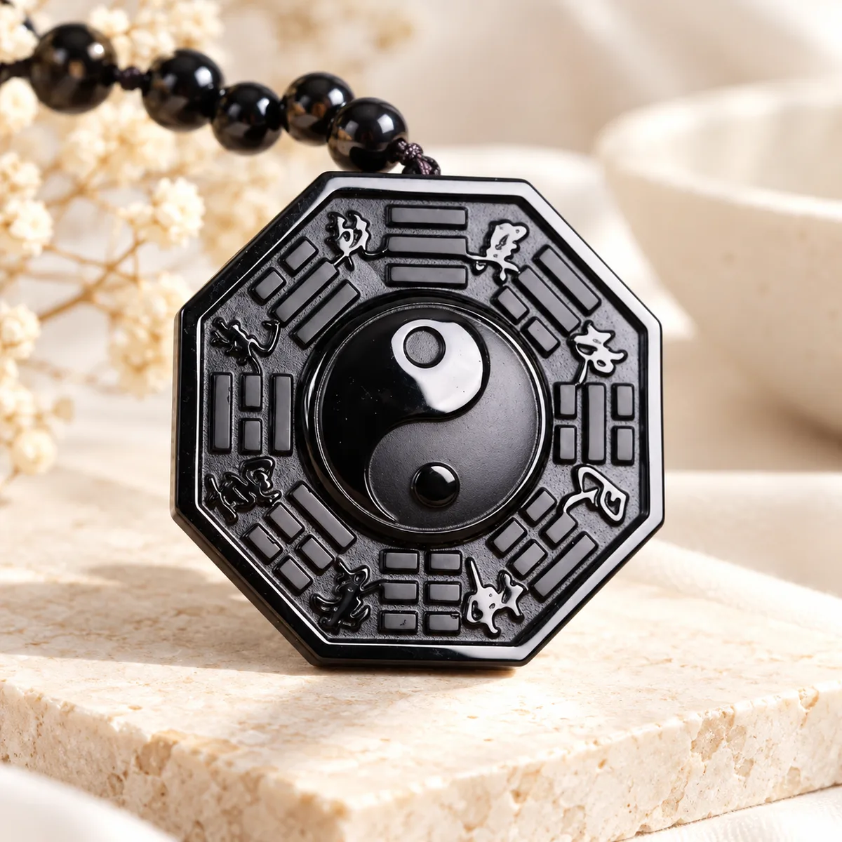 Pendentif bagua octogonal obsidienne Pendentif octogonal en obsidienne, huit trigrammes gravés autour d'un yin yang