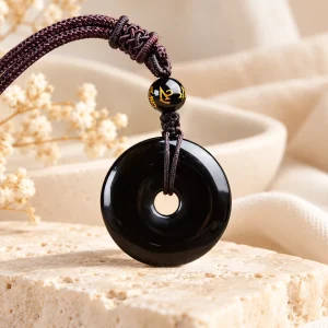 Pendentif donut en obsidienne noire, disque percé au centre, sur cordon brun