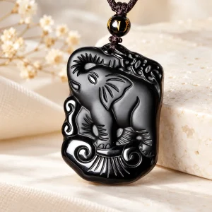Pendentif en obsidienne, éléphant sculpté en relief, trompe levée sur un nuage stylisé