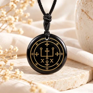 Pendentif disque d'obsidienne gravé d'un sceau à double cercle et croix, rehaussé d'or