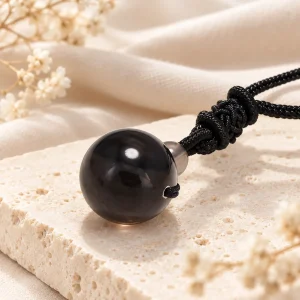 Pendentif en sphère d'obsidienne argentée au voile gris froid, sur cordon noir